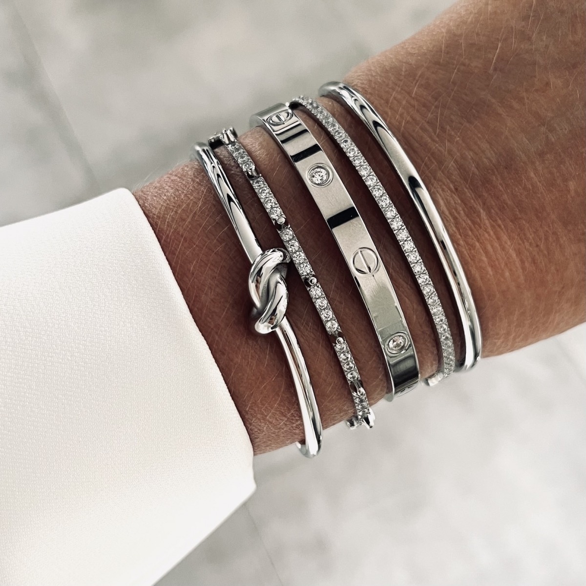 Five polished silver bracelets worn together